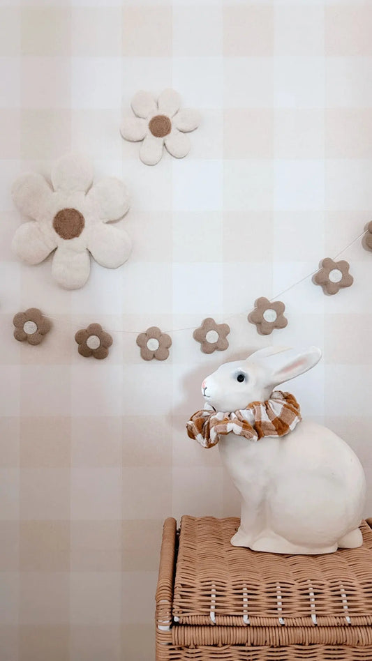 Guirlande décorative de fleurs beiges suspendue dans une chambre de bébé aux tons naturels