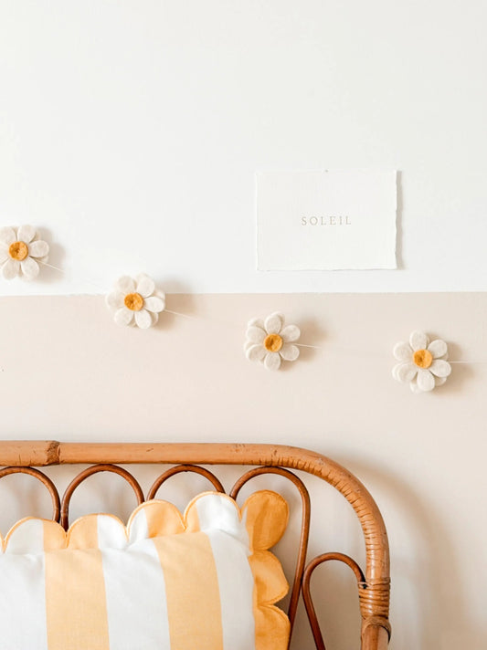 Guirlande décorative de fleurs jaunes en laine feutrée dans une chambre de bébé aux tons naturels