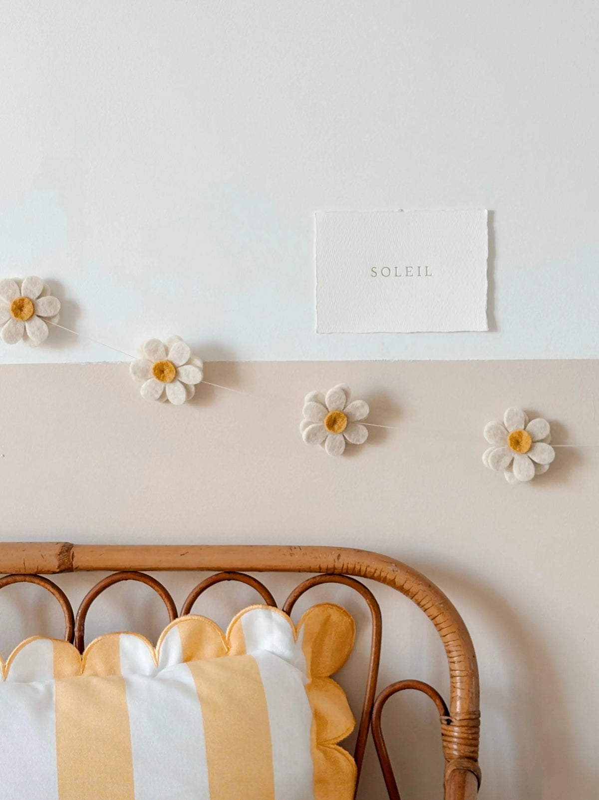 Guirlande florale jaune et écrue suspendue au mur au-dessus d'un lit bébé en rotin