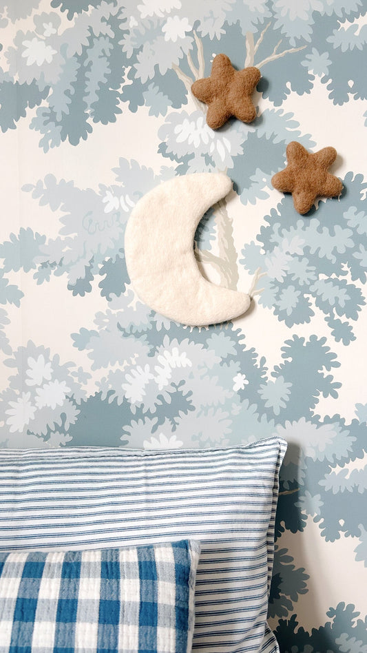 Décoration murale lune et étoiles suspendue dans une chambre de bébé aux tons naturels