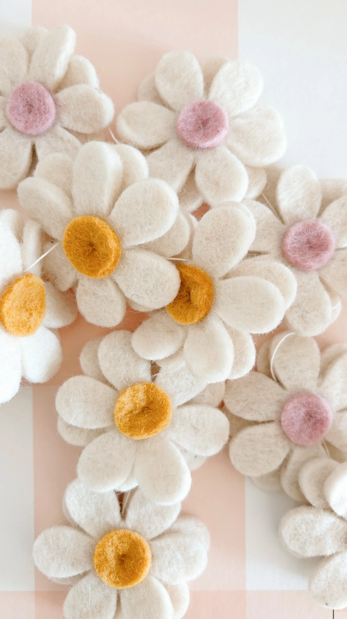 Gros plan sur les fleurs blanches, jaunes et rose poudré de la guirlande artisanale Bee Bohème