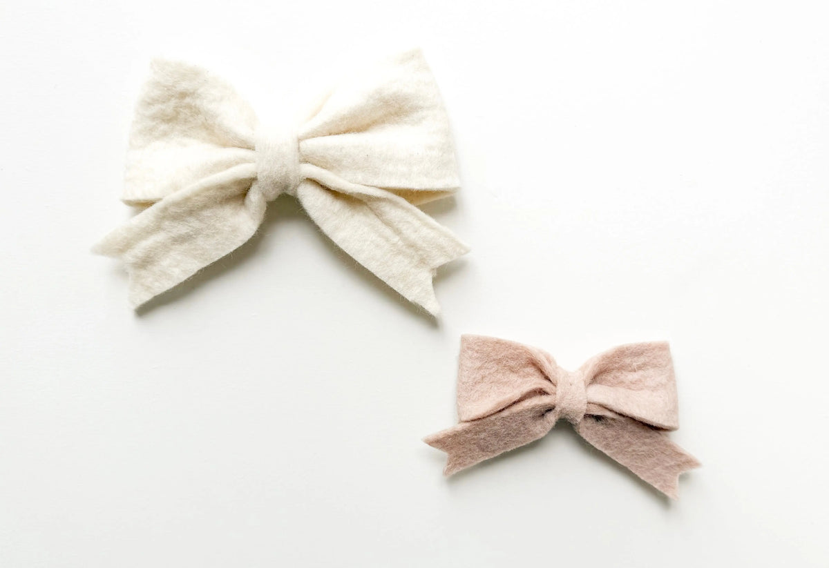 Détail du duo de nœuds en laine feutrée blanc et rose poudré, fabriqués artisanalement