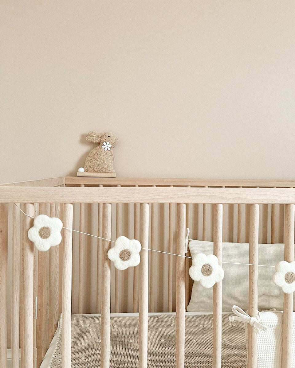 Guirlande fleurs écrues en laine feutrée dans une chambre de bébé