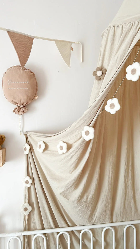 Guirlande de fleurs en laine feutrée sur un ciel de lit bébé