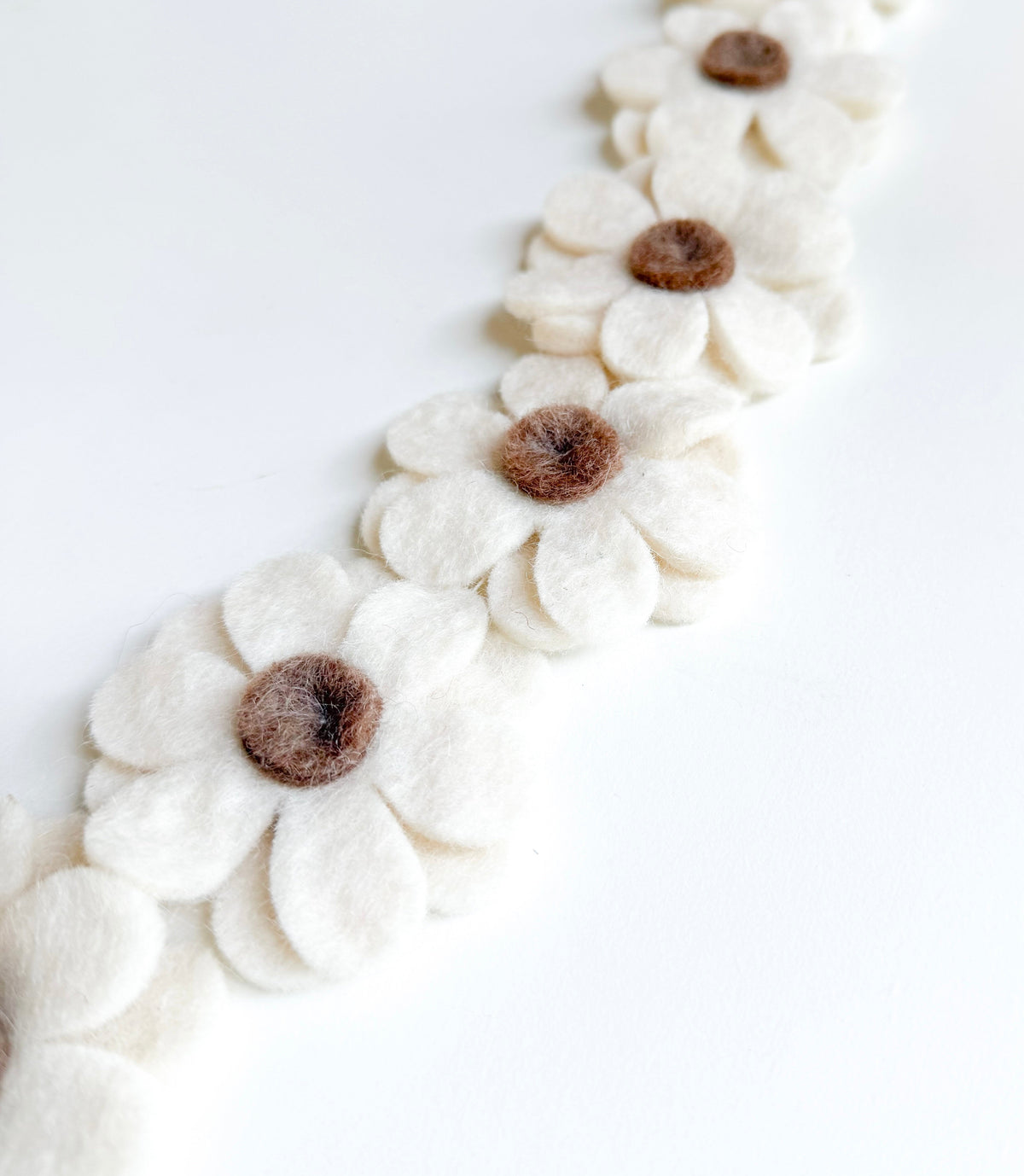 Détail des fleurs marron et écrues de la guirlande en laine feutrée