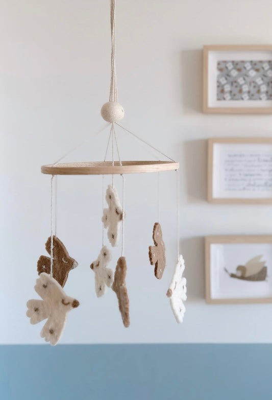 Maxi mobile décoratif oiseaux en laine feutrée, suspendu dans une chambre de bébé aux tons naturels.